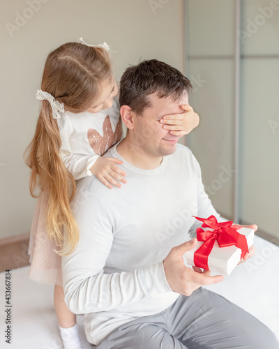 Father's day or Birthday concept. Happy daughter congratulating dad and giving present at home