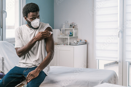 African American man patient holding cotton with alcohol disinfecting arm after covid vaccine procedure in clinic during coronavirus outbreak photo