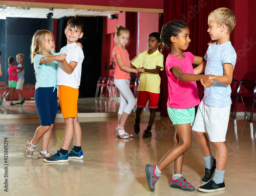 Smiling kids primary school trying dancing of partner dance in modern dance studio