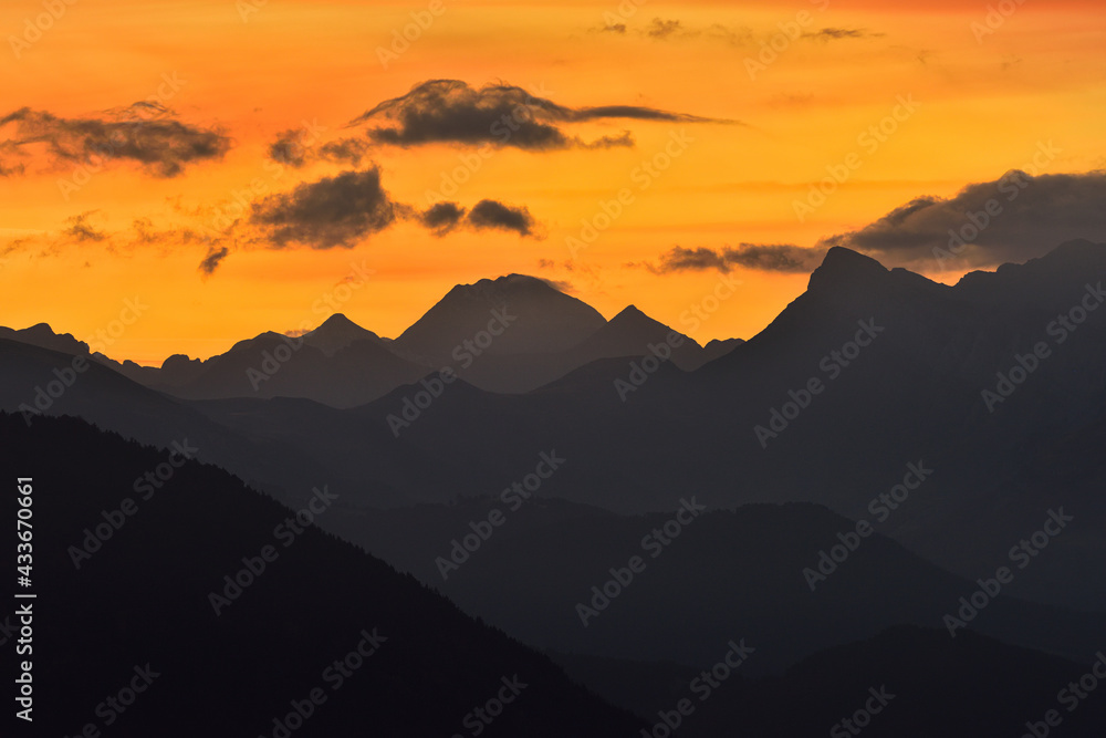 Breathtaking view of silhouettes of mountain peaks on background of bright orange sundown sky Breathtaking view of silhouettes of mountain peaks on background of bright orange sundown sky