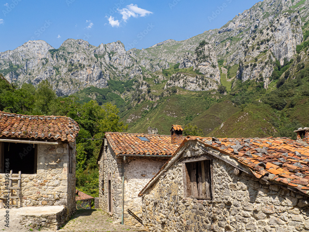 Vistas de las fachadas de unas casas rurales de piedra  con las montañas de fondo , en el pueblo de San Esteban de Cuñaba en Asturias, España, verano de 2020
