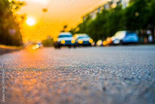 Sunset in the city, the cars driving on the road. Close up view from the asphalt level