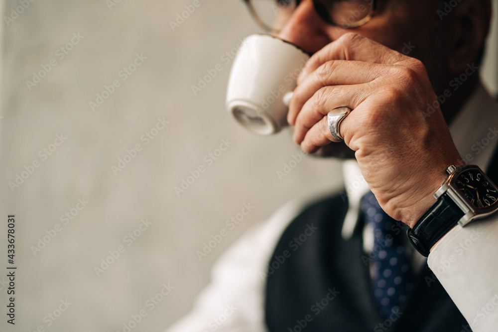 Crop ethnic male entrepreneur in formal wear and wristwatch enjoying hot beverage from cup while looking away in coffee shop Crop ethnic male entrepreneur in formal wear and wristwatch enjoying hot beverage from cup while looking away in coffee shop