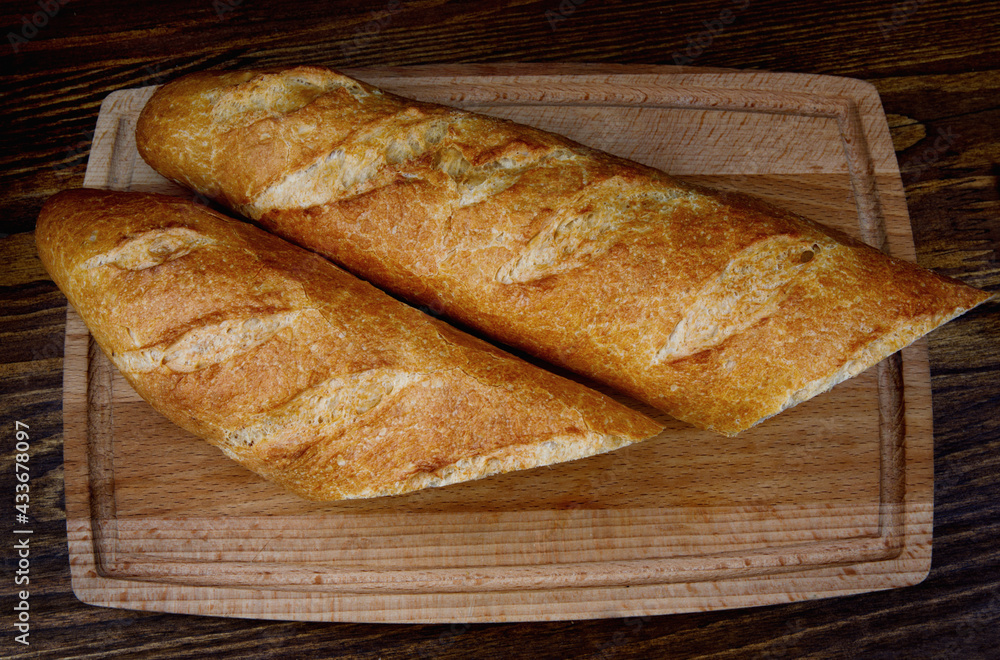 Two French baguettes on a cutting board.