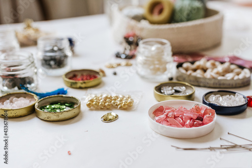 Side view of various decorative bugle beads in metal containers on wooden table