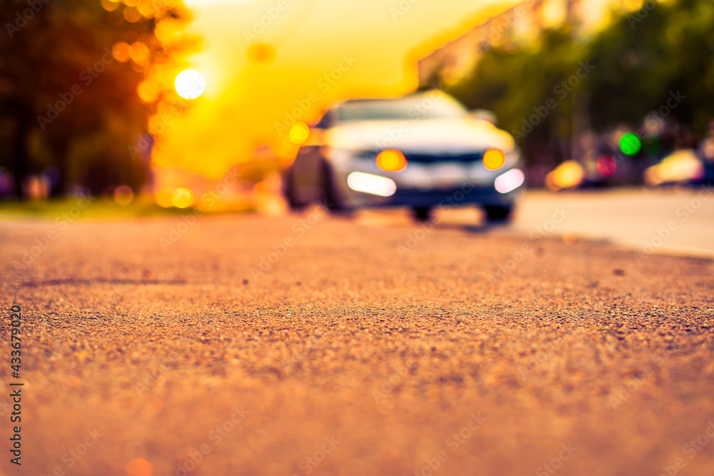 Sunset in the city, the car parked on the road. Close up view from the sidewalk level Sunset in the city, the car parked on the road. Close up view from the sidewalk level