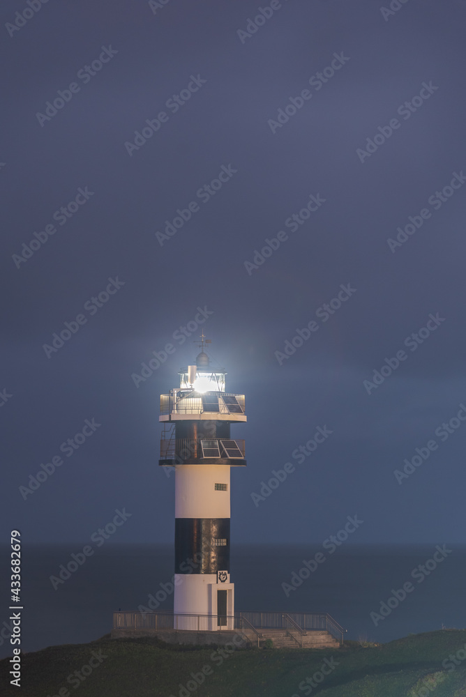 Picturesque scenery of grassy shore with lighthouse placed near blue ocean in Faro Illa Pancha in Galicia in Spain at night Picturesque scenery of grassy shore with lighthouse placed near blue ocean in Faro Illa Pancha in Galicia in Spain at night