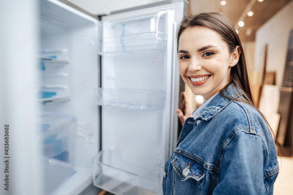 Young attractive woman choosing refrigerator in hypermarket Young attractive woman choosing refrigerator in hypermarket
