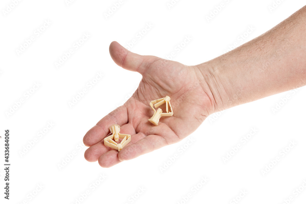 Hand holds a plastic dowel for screws on a white background Hand holds a plastic dowel for screws on a white background