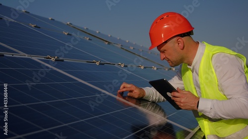 Caucasian man technician using laptop computer checking Solar Cell panels. Engineer repair and maintenance photovoltaic
