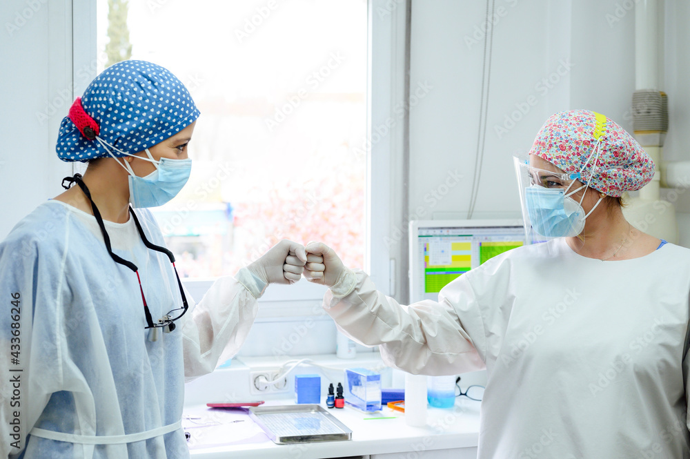 Doctors in uniforms greeting each other with high five at work in hospital Doctors in uniforms greeting each other with high five at work in hospital