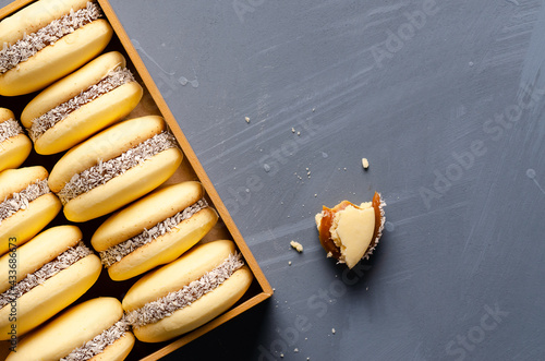 Photos Cornstarch alfajores with milk caramel and coconut on a wooden box