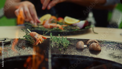 Man and woman preparing food for grill party. Shrimp grilling with herbs