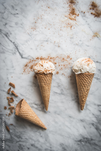 Overhead view of tasty waffle cones with creamy meringue milk gelato scoops on marble table photo