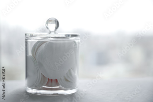 Clear container for cotton pads on a grey background. 