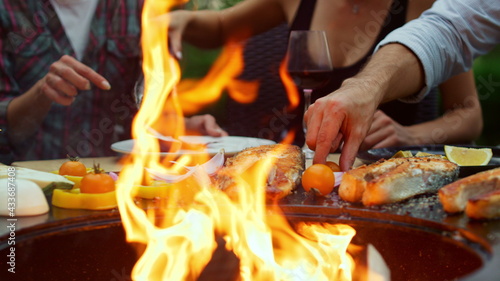 Happy fellows grilling dinner on backyard. Unknown woman cooking bbq food