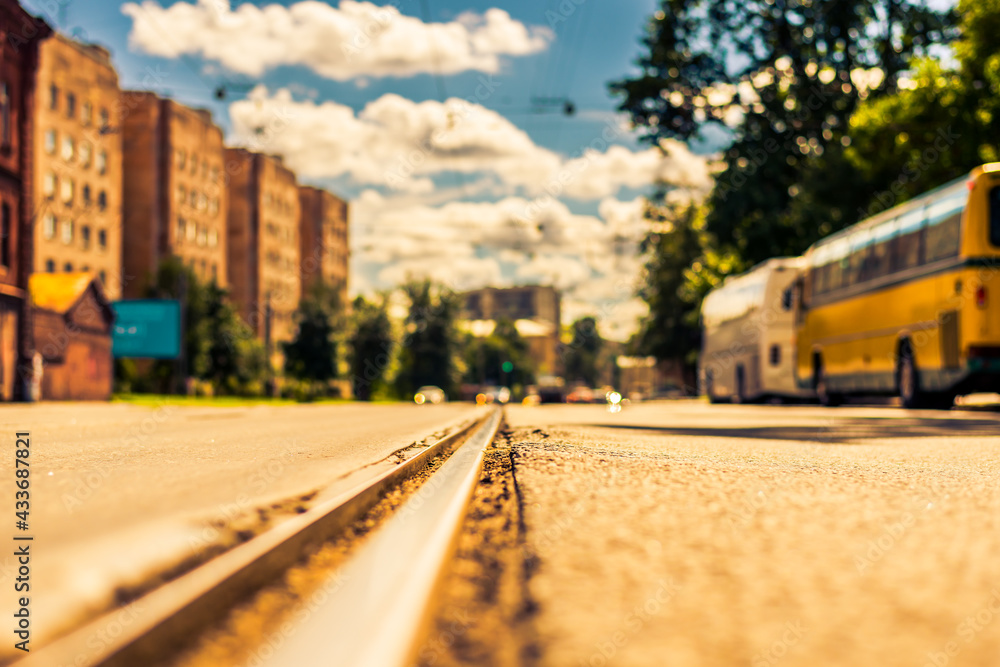 Summer in the city, the street with tramway rails and parked buses. Close up view of a tram rail level