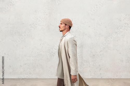 Serious male wearing trendy coat and hat standing in city and looking away photo