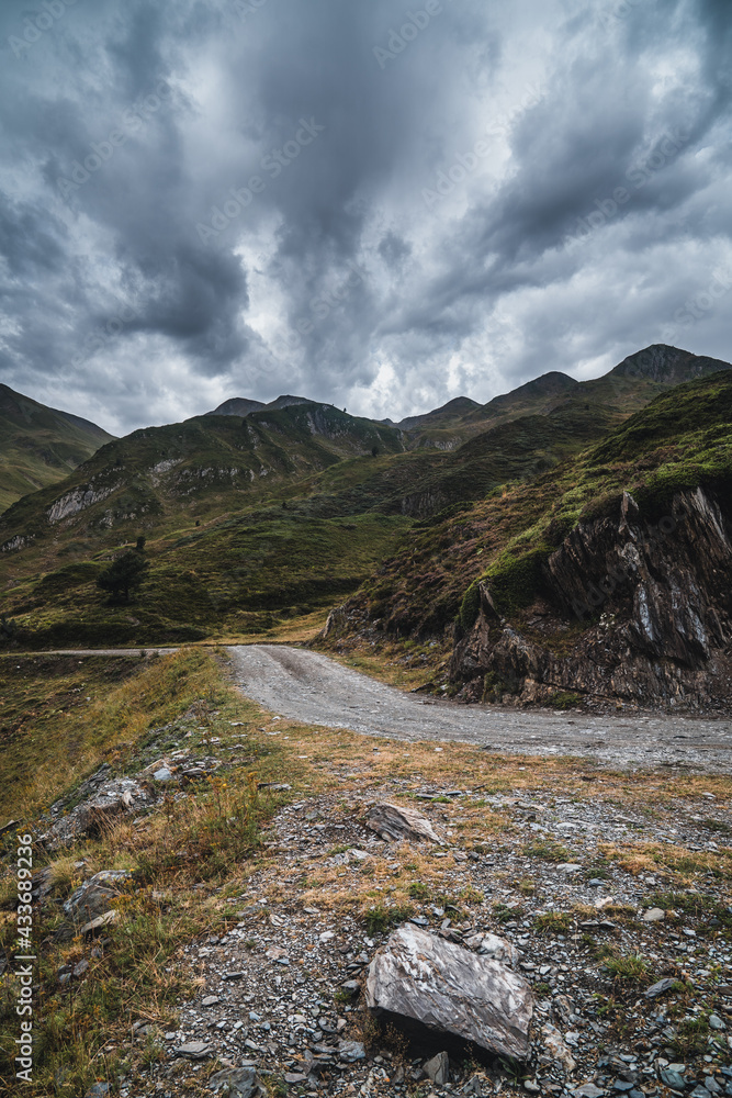 Picturesque landscape of empty route surrounded with dry and green grass in mountainous terrain of Aran Valley in Spain under gray cloudy sky Picturesque landscape of empty route surrounded with dry and green grass in mountainous terrain of Aran Valley in Spain under gray cloudy sky