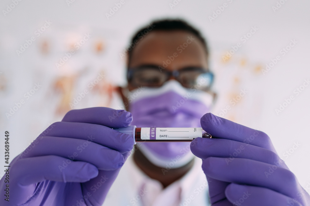 African American male doctor in medical glove demonstrating test tube with blood sample on white background African American male doctor in medical glove demonstrating test tube with blood sample on white background