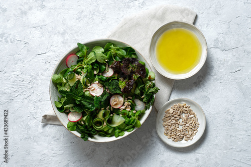 Top view of fresh healthy vegetable salad in bowl served on table with olive oil and sunflower seeds