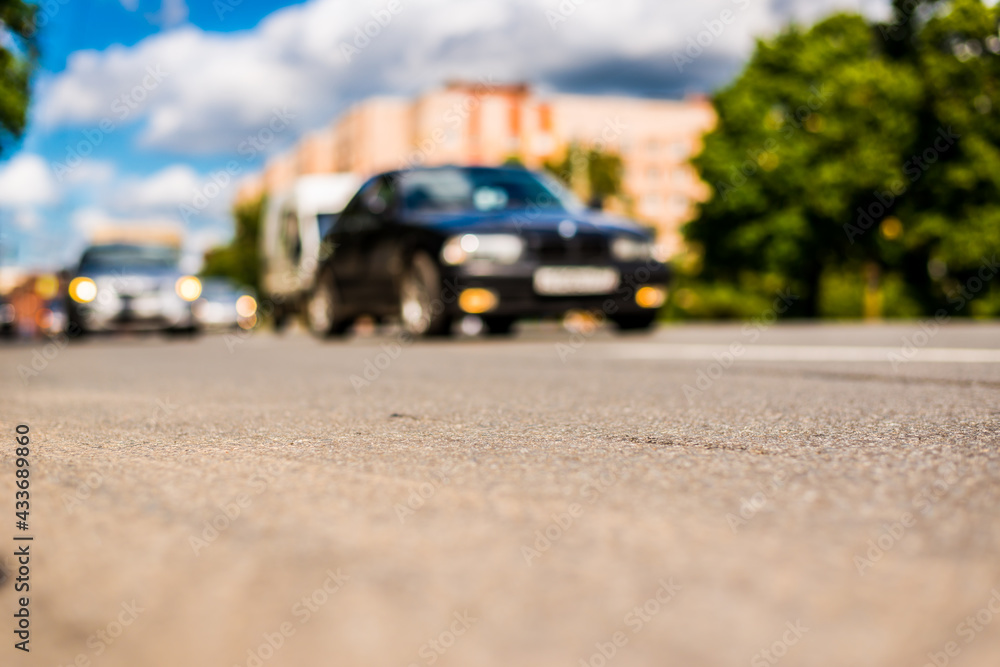 Obraz premium Summer in the city, the cars driving on the street. Close up view from the asphalt level