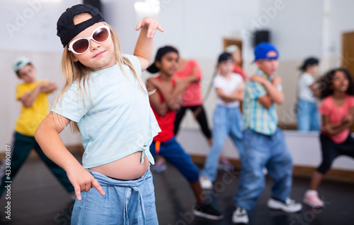 Portrait of emotional girl doing hip hop movements during group class in dance studio