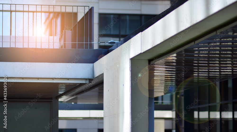 Fototapeta premium Modern architecture with sun ray. Glass and steel facade on a bright sunny day with sunbeams on the blue sky. Economy, finances, business activity concept.