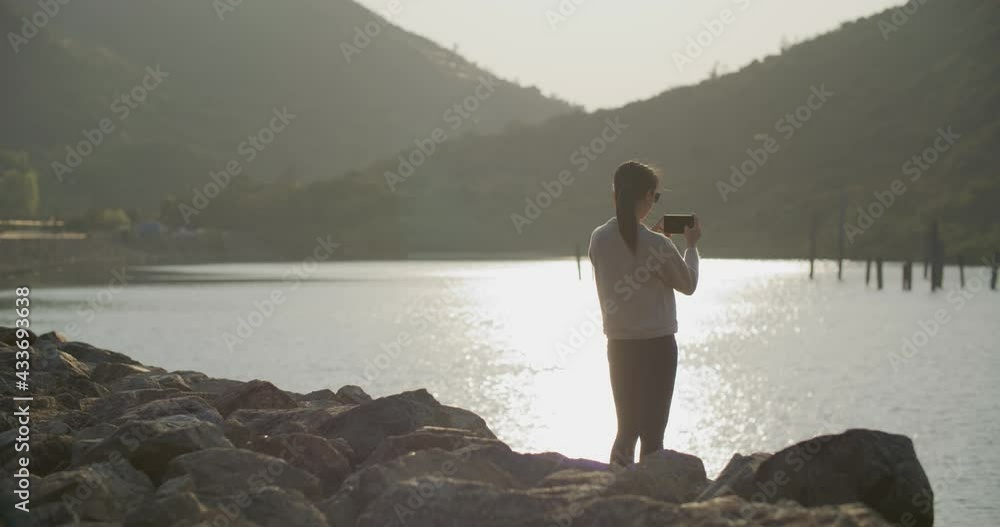 Woman use of mobile phone to take photo in sunset time Woman use of mobile phone to take photo in sunset time