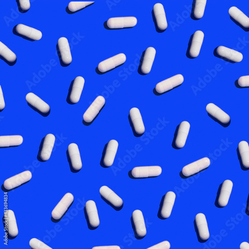 White pills pattern flat lay in blue background