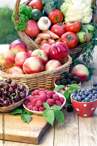 Fresh organic fruits and vegetables in bowls and baskets on table