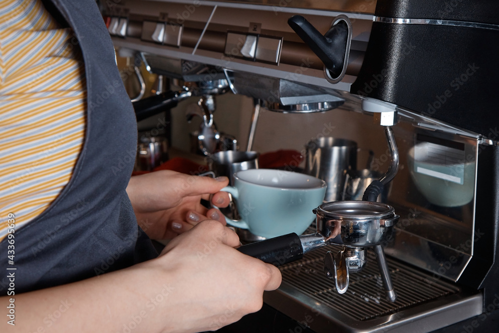 barista prepares and pours coffee into a mug on the coffee machine, close-up, hands of a woman, blurred background barista prepares and pours coffee into a mug on the coffee machine, close-up, hands of a woman, blurred background