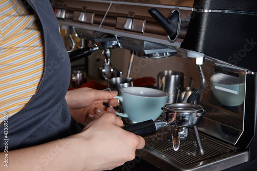 barista prepares and pours coffee into a mug on the coffee machine, close-up, hands of a woman, blurred background © Илья ивашкевич