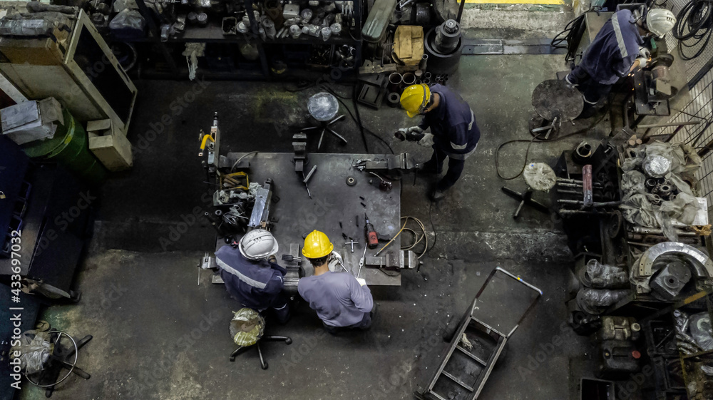 Top view of technician and engineer team work to maintain the machinery part in the industry factory, Machanic serrvice team are cutting and grinding part in the workshop