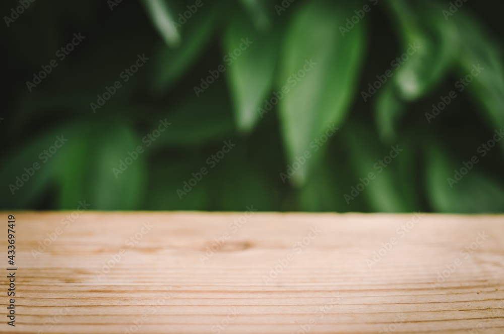 Wooden table close-up with blurred natural background. Green natural blurred background with wooden table for product advertising