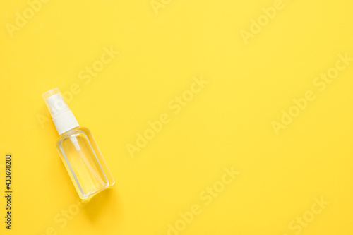 top view of alcohol spray in transparent plastic bottle on yellow background  Coronavirus protection equipment background concept.