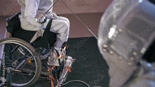 disabled athlete. fencing. sparring in fencing duel of two wheelchair fencing athletes with reduced physical abilities. They practice fight duel technique during workout. photo