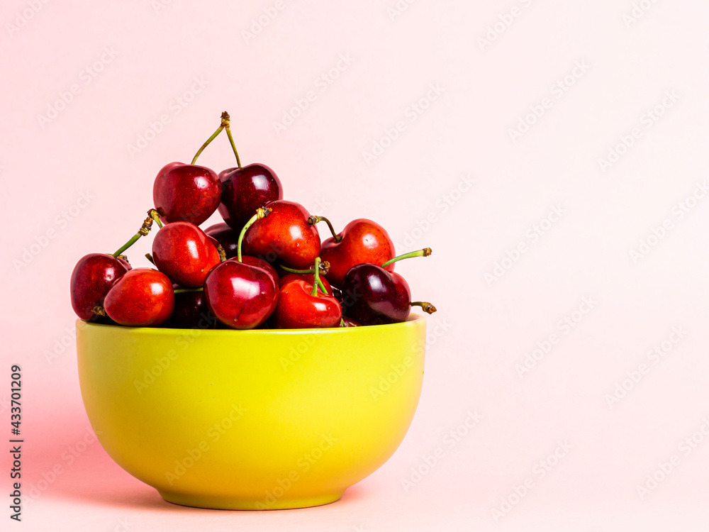 Green bowl with cherries on a white background with copy space. Green bowl with cherries on a white background with copy space.