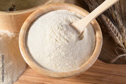 Photos Whole wheat durum flour in wooden bowl with spoon on a natural wooden background
