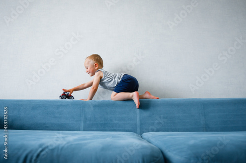 A little boy plays with a toy car on the couch.