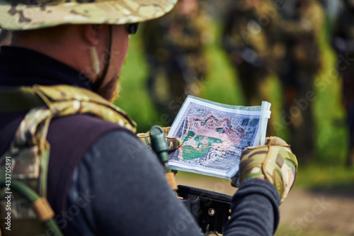 Airsoft player in military uniform examining a map