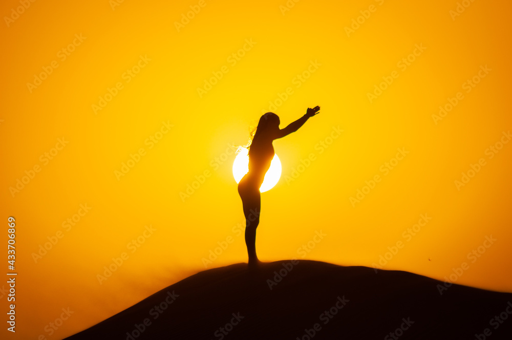 Silhouette of a young woman doing yoga pose at sunset
