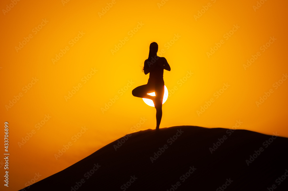 Silhouette of a young woman doing yoga pose at sunset Silhouette of a young woman doing yoga pose at sunset