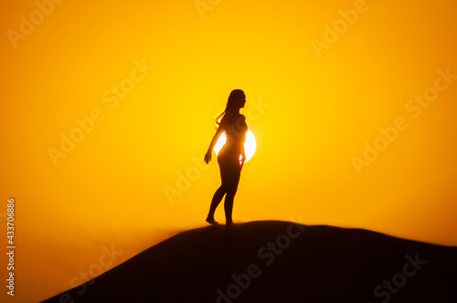 Silhouette of a young woman doing yoga pose at sunset