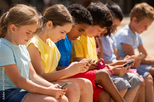 Group of children communicate using smartphones in the playground