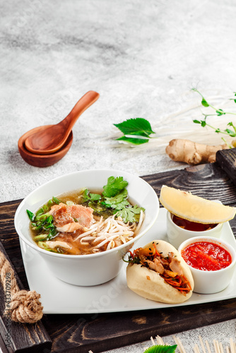 Asian noodle soup. Ramen with beef, tofu and vegetables in white plate on concrete background. Close up.  photo