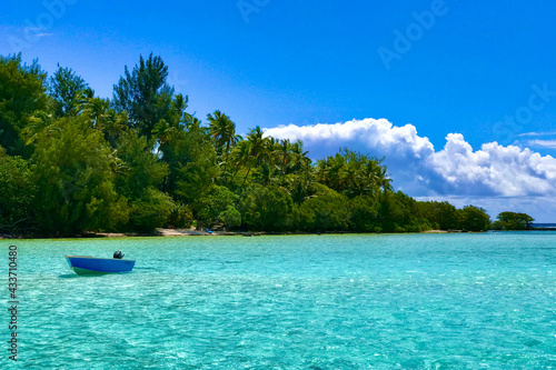 small blue boat close to Moorea motu in shallow water