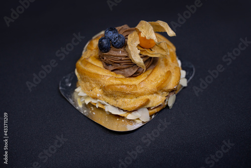 fresh pastries for breakfast: a cake in the form of a nest with cream and berries on a black background