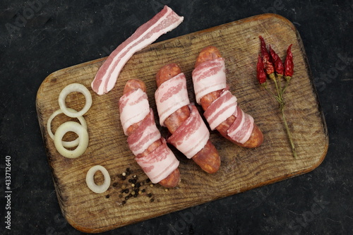 Chorizo Sausages Wrapped In Bacon on Wooden Cutting Board. Raw Sausages In Natural Casing Wrapped In Pork Bacon. Bacon Wrapped Sausages on Wood.