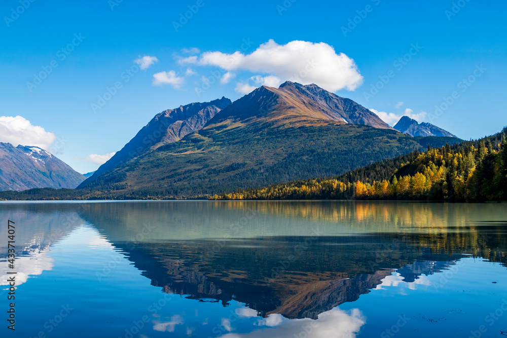 mountain and autumn foliage of trees reflection on a calm lake in the Kenai peninsula in Alaska.